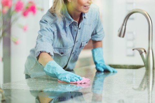 A woman uses countertop cleaning tips to safely protect her kitchen counters.