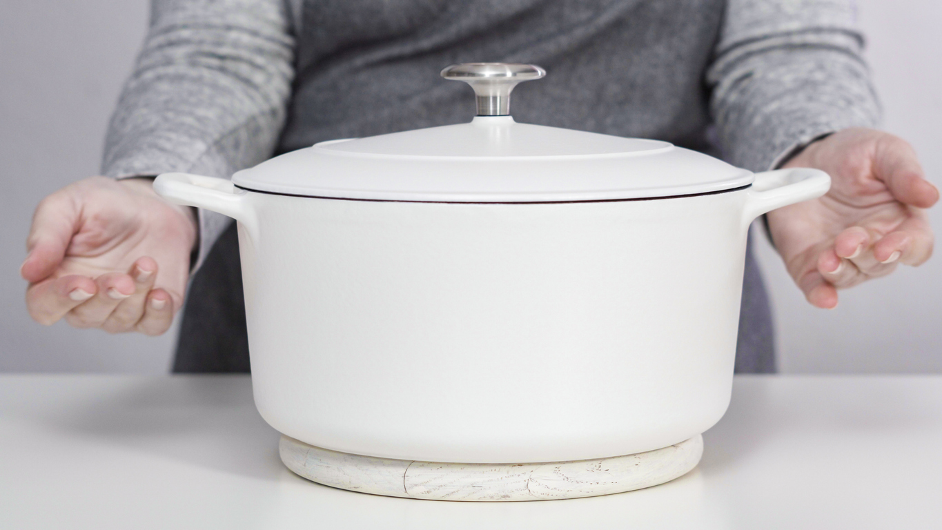 Hot pot resting on a trivet on a light stone countertop beside the range.