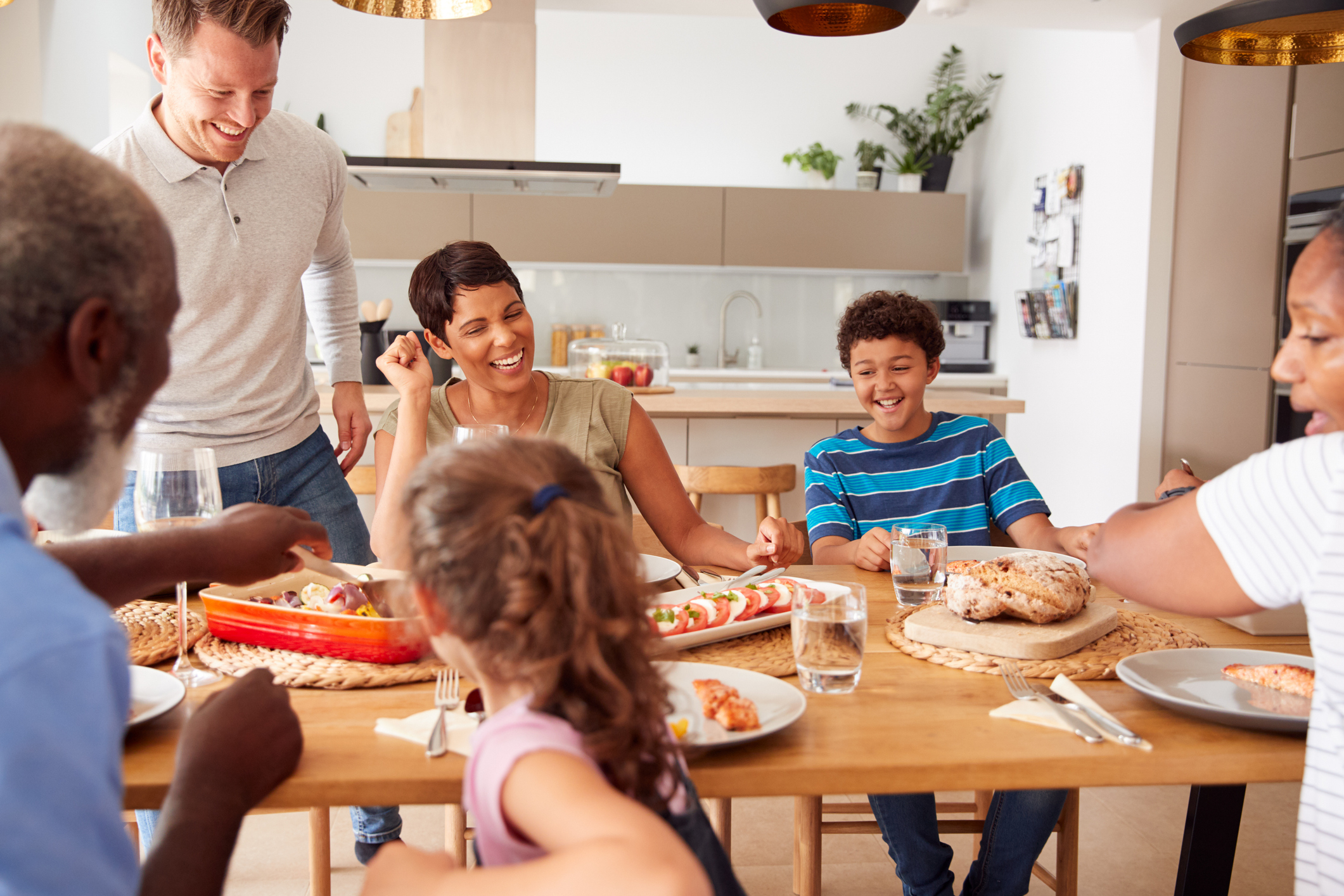 A family gathers around the kitchen table to enjoy food together.