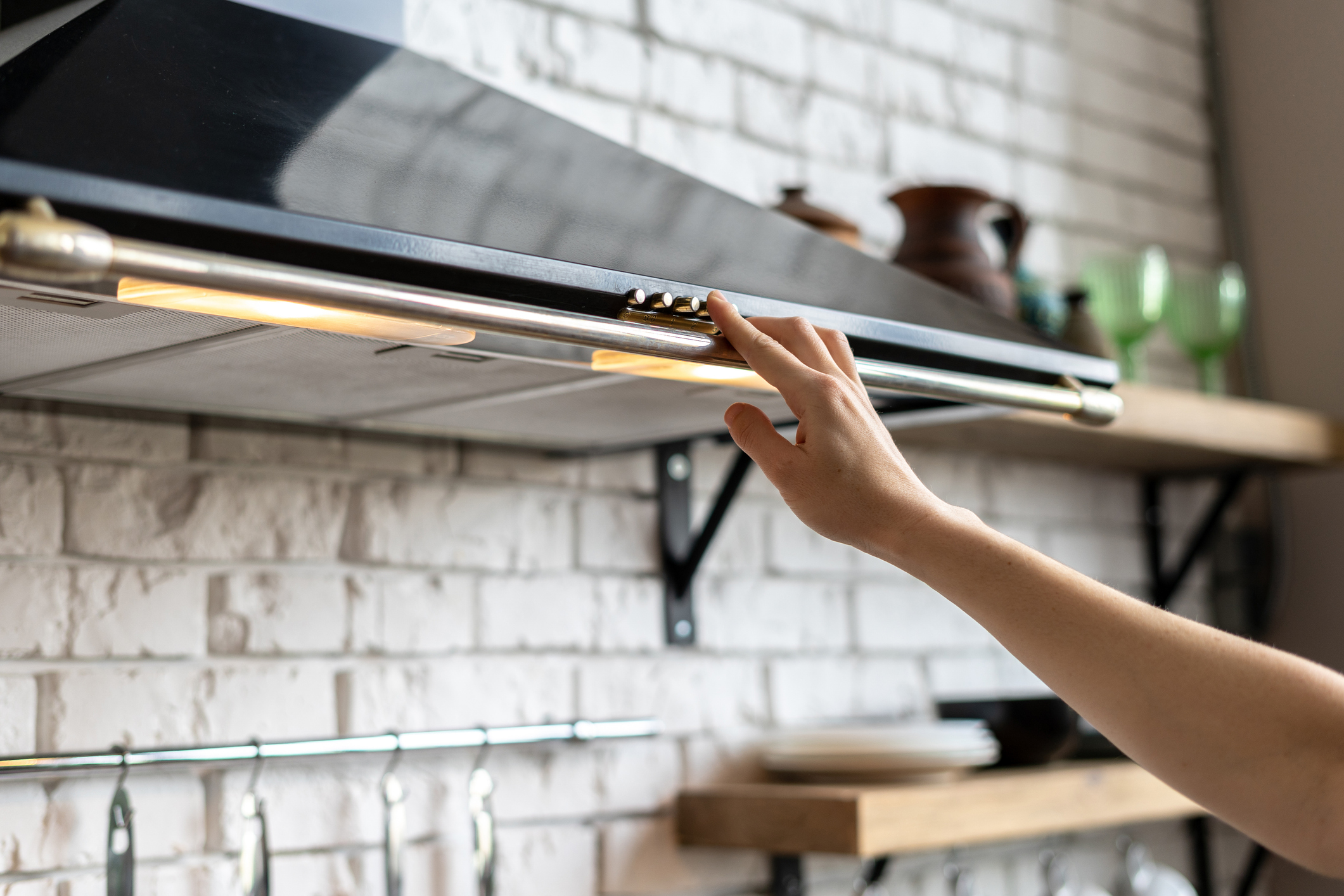 A homeowner turns on the fan on her range hood to remove hot air and smoke from her kitchen.
