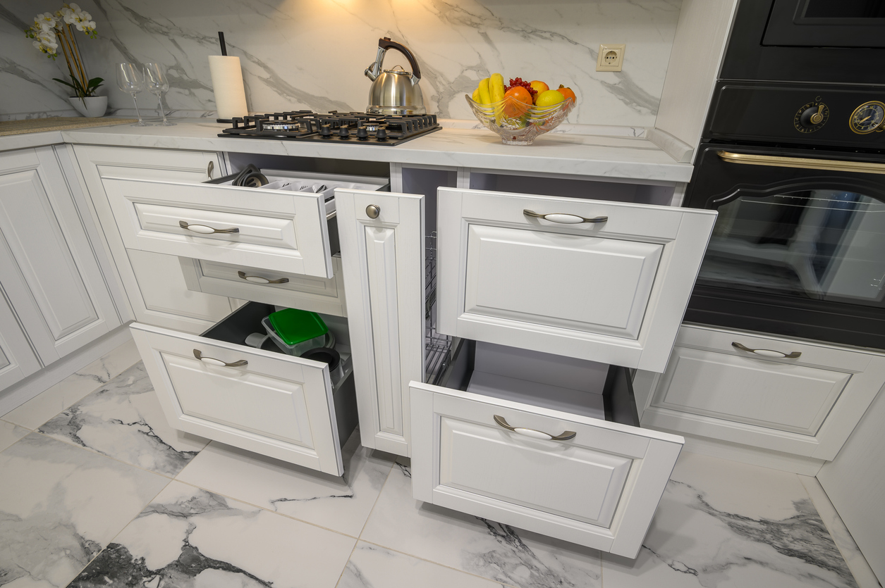Open kitchen cabinet with pull-out shelf holding organized lunch containers and snack items for school lunch prep.