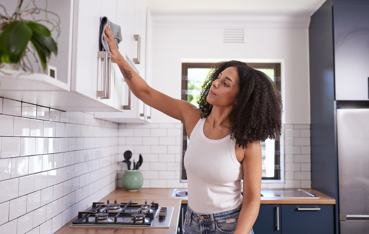 A woman thoroughly cleaning her kitchen cabinets before she starts painting.