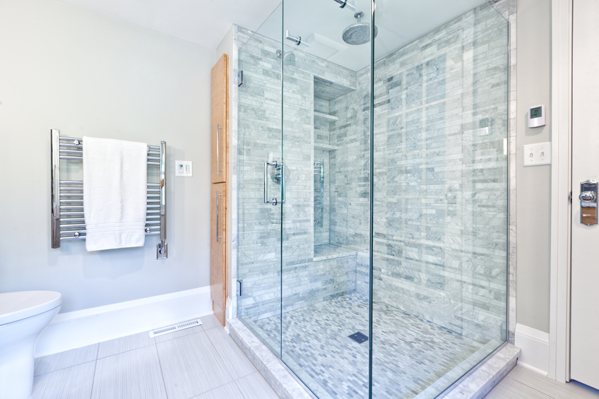 KDI Kitchen spa-style bathroom with frameless glass shower and marble tile bench seating